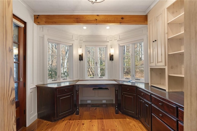 unfurnished office with crown molding, built in desk, and light wood-type flooring