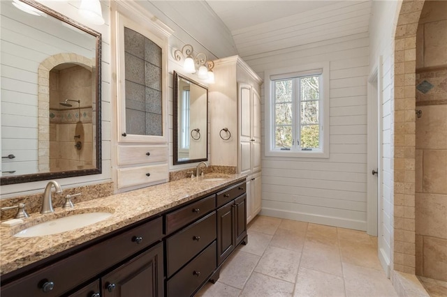 bathroom featuring vanity, a shower, and wooden walls