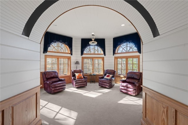 sitting room featuring light colored carpet, french doors, and wooden walls