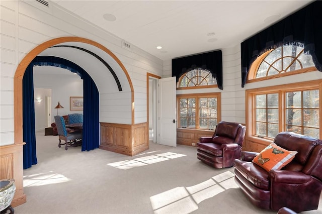 sitting room featuring light carpet and wood walls