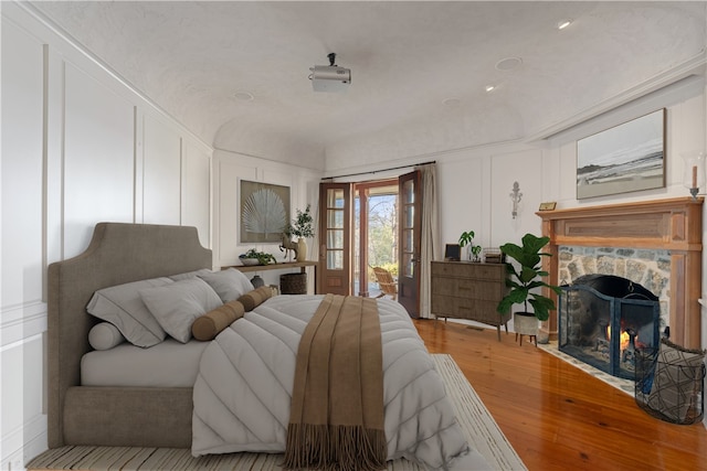 bedroom featuring light wood-type flooring and a stone fireplace