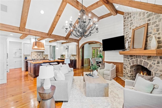 604 Top Ridge Dr, Sunset, SC 29685 - living area featuring light wood finished floors, arched walkways, vaulted ceiling with beams, an inviting chandelier, and a stone fireplace