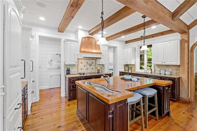 604 Top Ridge Dr, Sunset, SC 29685 - kitchen featuring custom exhaust hood, a center island with sink, light wood finished floors, backsplash, and white cabinetry