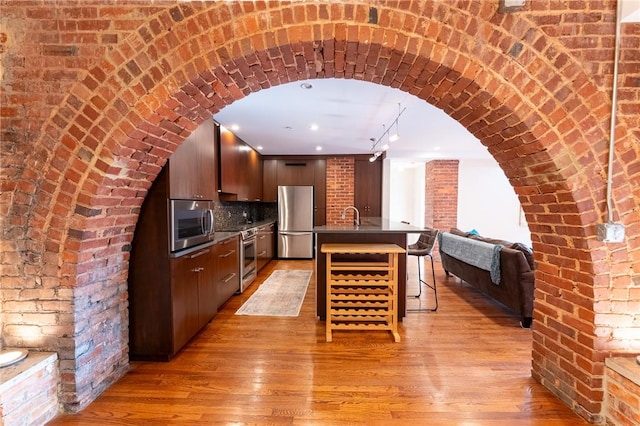 kitchen with arched walkways, a breakfast bar, stainless steel appliances, open floor plan, and modern cabinets