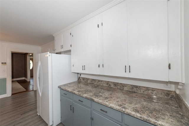 kitchen featuring dark wood-type flooring, white fridge, and white cabinetry