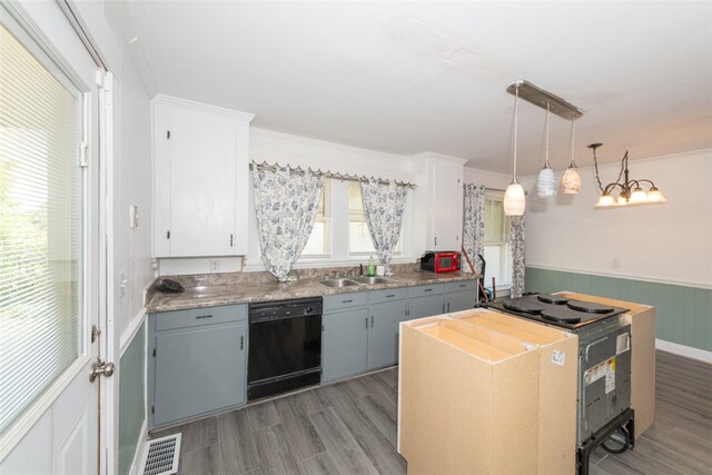 kitchen with white cabinets, wood walls, decorative light fixtures, light hardwood / wood-style flooring, and dishwasher