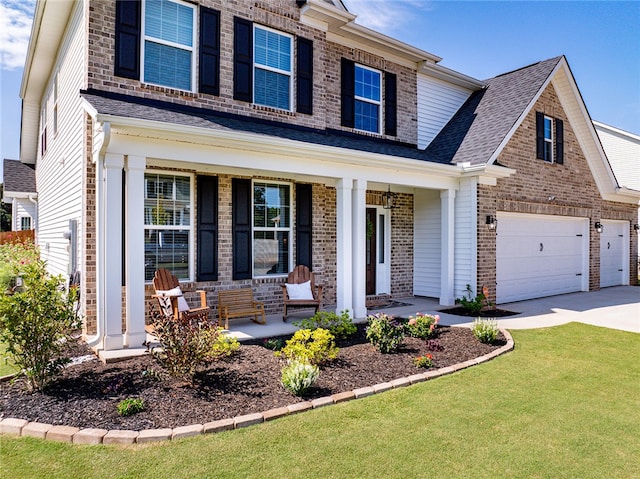 view of front of home with covered porch, a front yard, and a garage