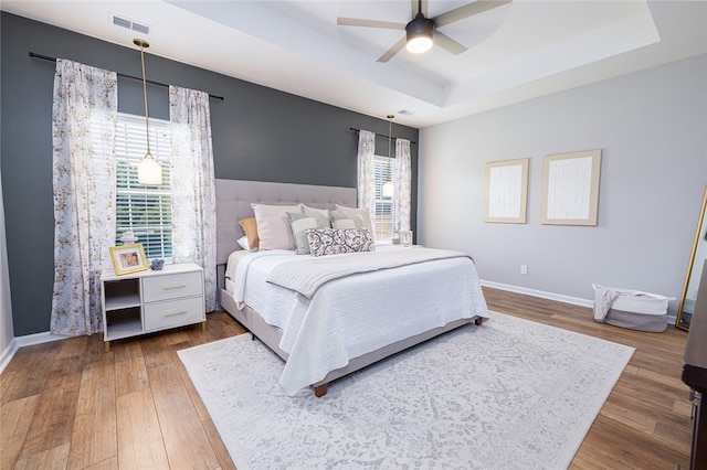 bedroom with a tray ceiling, multiple windows, and ceiling fan