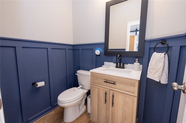 bathroom with wood-type flooring, vanity, and toilet