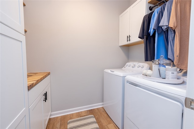 washroom featuring separate washer and dryer, cabinets, and light hardwood / wood-style flooring