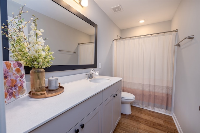 bathroom with walk in shower, wood-type flooring, vanity, and toilet