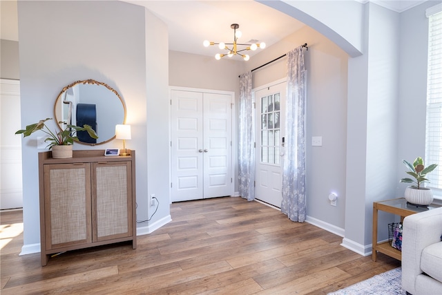 foyer entrance with a healthy amount of sunlight, light hardwood / wood-style floors, and a notable chandelier