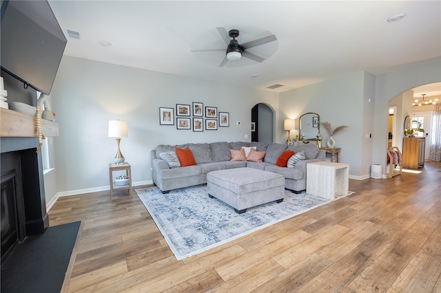 living room with ceiling fan with notable chandelier and hardwood / wood-style floors