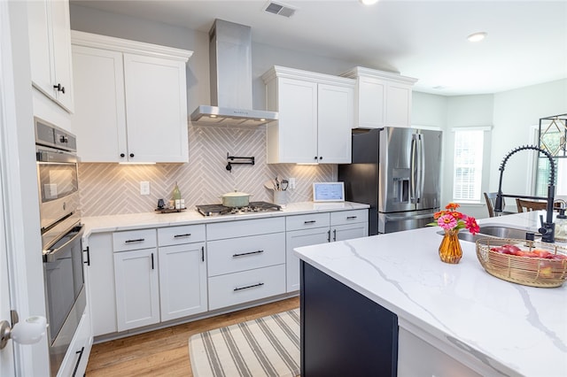 kitchen featuring white cabinets, appliances with stainless steel finishes, and wall chimney exhaust hood