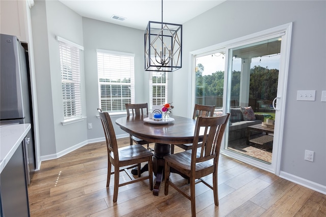 dining space with light hardwood / wood-style floors, an inviting chandelier, and plenty of natural light