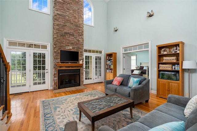 living room with french doors, light wood-type flooring, a high ceiling, and a wealth of natural light