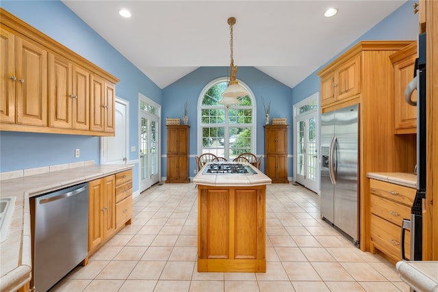 kitchen with hanging light fixtures, vaulted ceiling, a kitchen island, light tile patterned floors, and stainless steel appliances