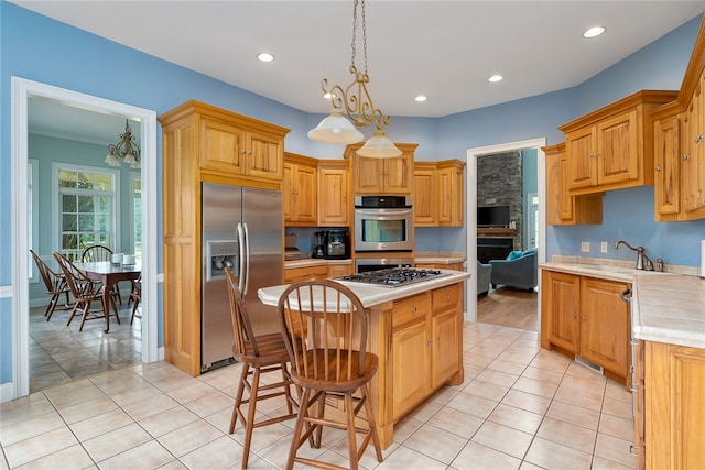 kitchen with an inviting chandelier, stainless steel appliances, sink, and a kitchen island