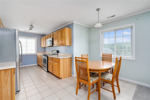 kitchen with hanging light fixtures, ornamental molding, light tile patterned floors, and stainless steel appliances