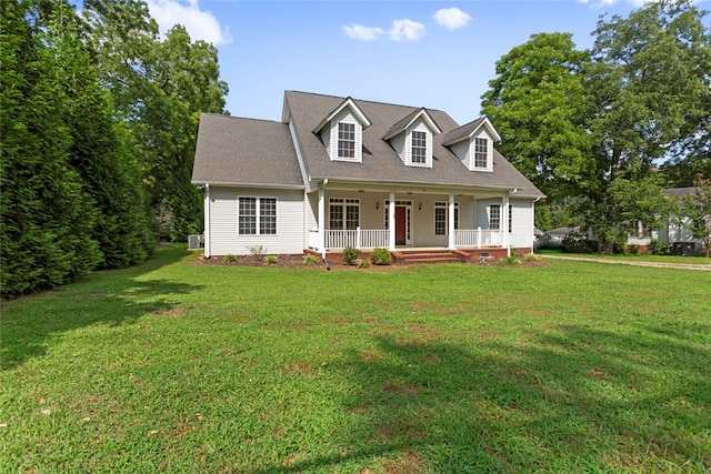 new england style home with cooling unit, a front yard, and covered porch