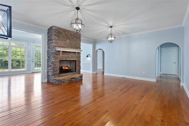 unfurnished living room featuring wood-type flooring, a stone fireplace, and ornamental molding