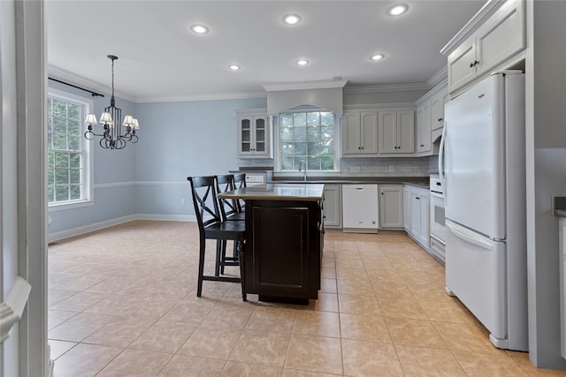 kitchen featuring light tile patterned flooring, a kitchen island, an inviting chandelier, white appliances, and backsplash