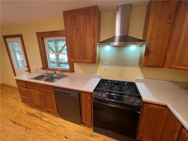 kitchen with light wood-type flooring, black appliances, wall chimney exhaust hood, and sink