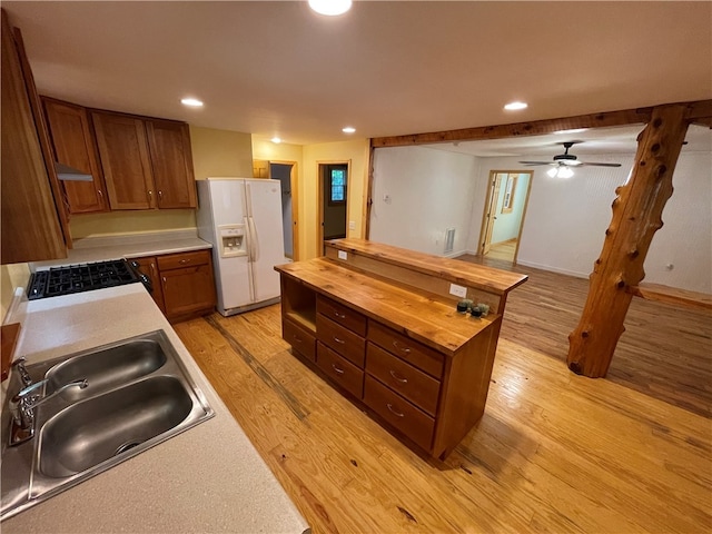 kitchen with white refrigerator with ice dispenser, wood counters, sink, light hardwood / wood-style flooring, and ceiling fan