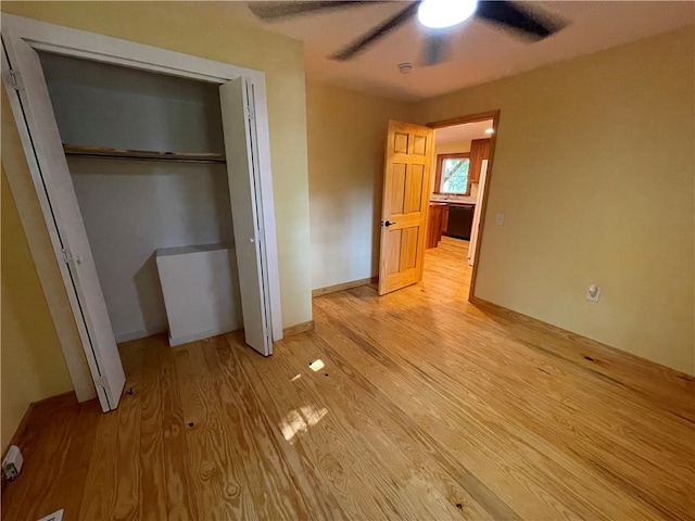 unfurnished bedroom with ceiling fan, light wood-type flooring, and a closet