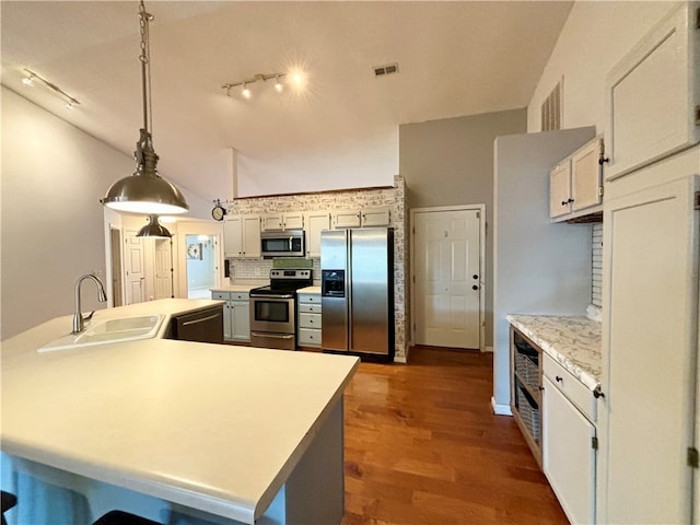 kitchen featuring appliances with stainless steel finishes, white cabinetry, dark hardwood / wood-style flooring, pendant lighting, and sink