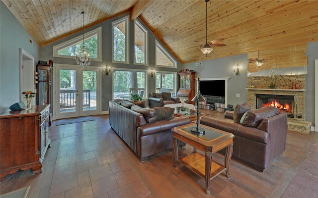 living room featuring wood ceiling, high vaulted ceiling, a stone fireplace, beamed ceiling, and french doors