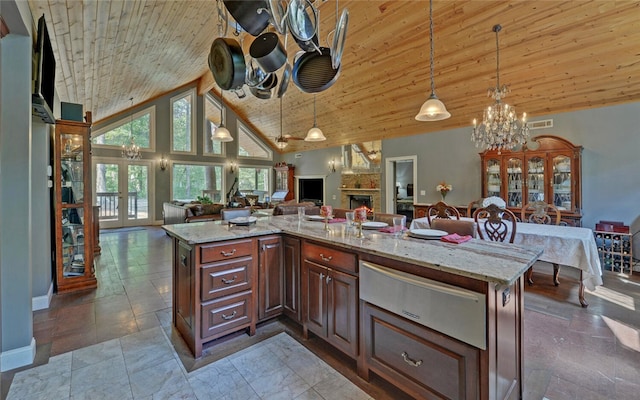 kitchen featuring light stone counters, hanging light fixtures, a stone fireplace, high vaulted ceiling, and a center island