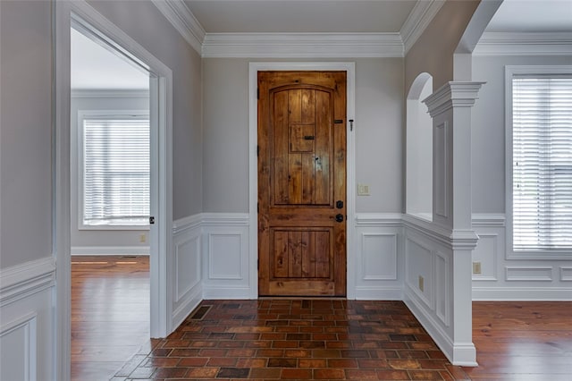 foyer entrance with decorative columns, dark hardwood / wood-style floors, and crown molding