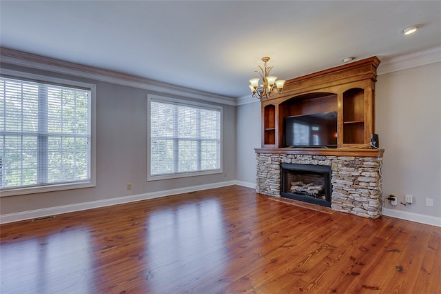 unfurnished living room with wood-type flooring, a stone fireplace, ornamental molding, and plenty of natural light