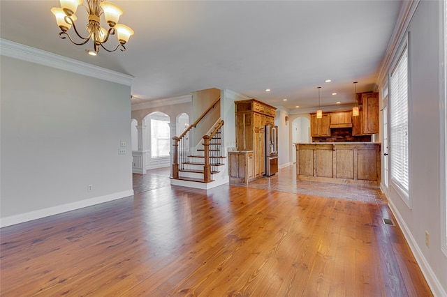 unfurnished living room with ornamental molding, a chandelier, and light hardwood / wood-style floors