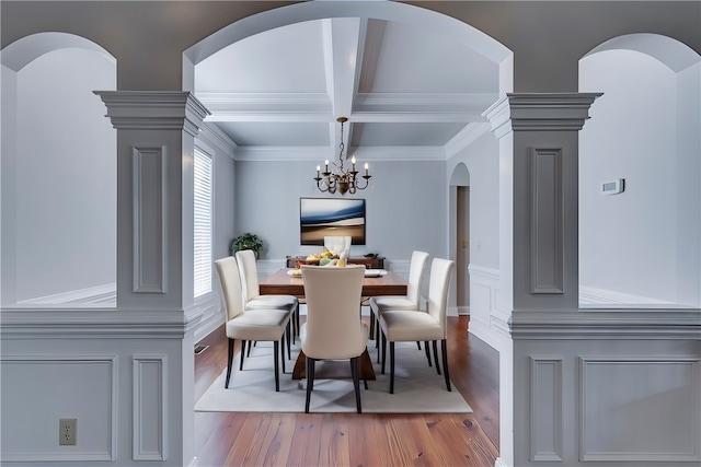 dining space with coffered ceiling, beam ceiling, hardwood / wood-style flooring, ornamental molding, and a chandelier