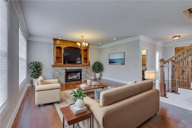 living room featuring ornamental molding, an inviting chandelier, a fireplace, and hardwood / wood-style floors