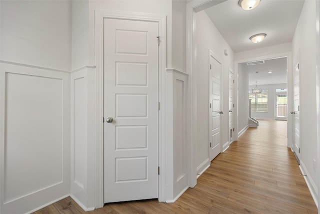 corridor with light hardwood / wood-style flooring and a chandelier