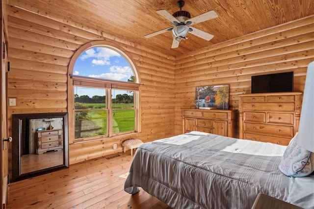 bedroom featuring wood ceiling, light hardwood / wood-style floors, ceiling fan, and rustic walls