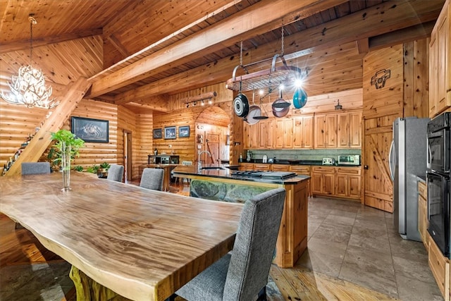 dining space with wood ceiling, beamed ceiling, sink, rustic walls, and a notable chandelier