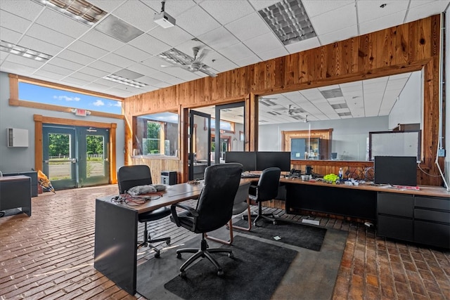 office area with a drop ceiling, wooden walls, ceiling fan, and french doors