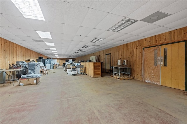 basement featuring a paneled ceiling and wood walls