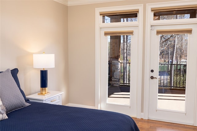 bedroom with ornamental molding, access to exterior, and light hardwood / wood-style floors