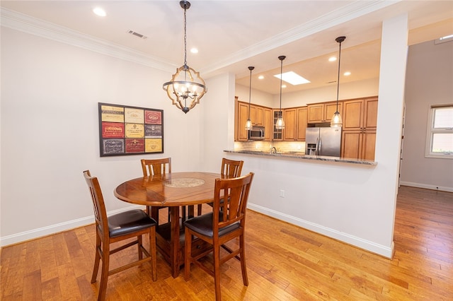 dining space featuring a notable chandelier, light wood-type flooring, and crown molding