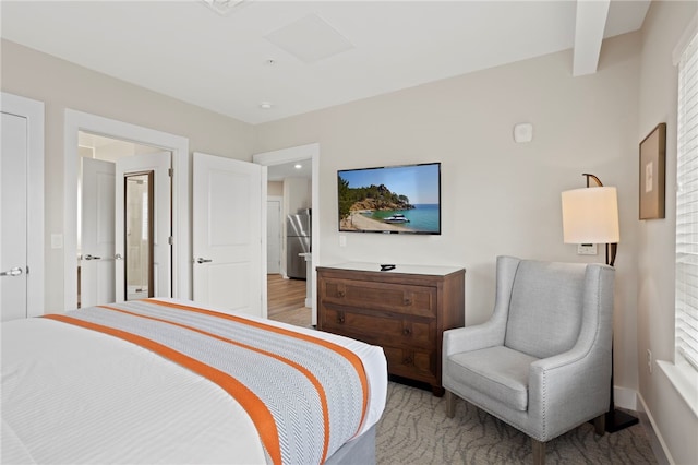 bedroom featuring stainless steel refrigerator and multiple windows