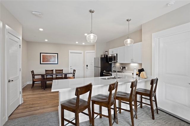 kitchen with kitchen peninsula, stainless steel appliances, dark wood-type flooring, white cabinets, and hanging light fixtures