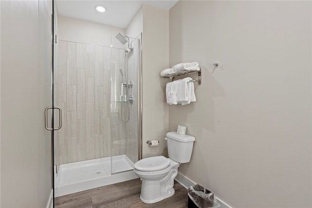 bathroom featuring hardwood / wood-style floors, toilet, and a shower with shower door