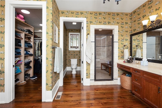 bathroom featuring wood-type flooring, vanity, walk in shower, and toilet