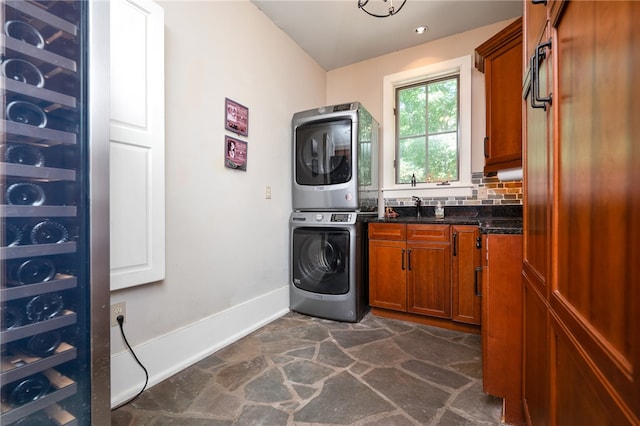 clothes washing area with stacked washer and clothes dryer, cabinets, and sink