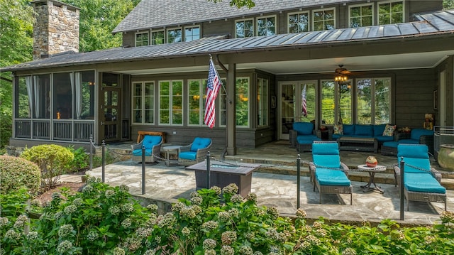 view of patio with ceiling fan, an outdoor living space with a fire pit, and a sunroom